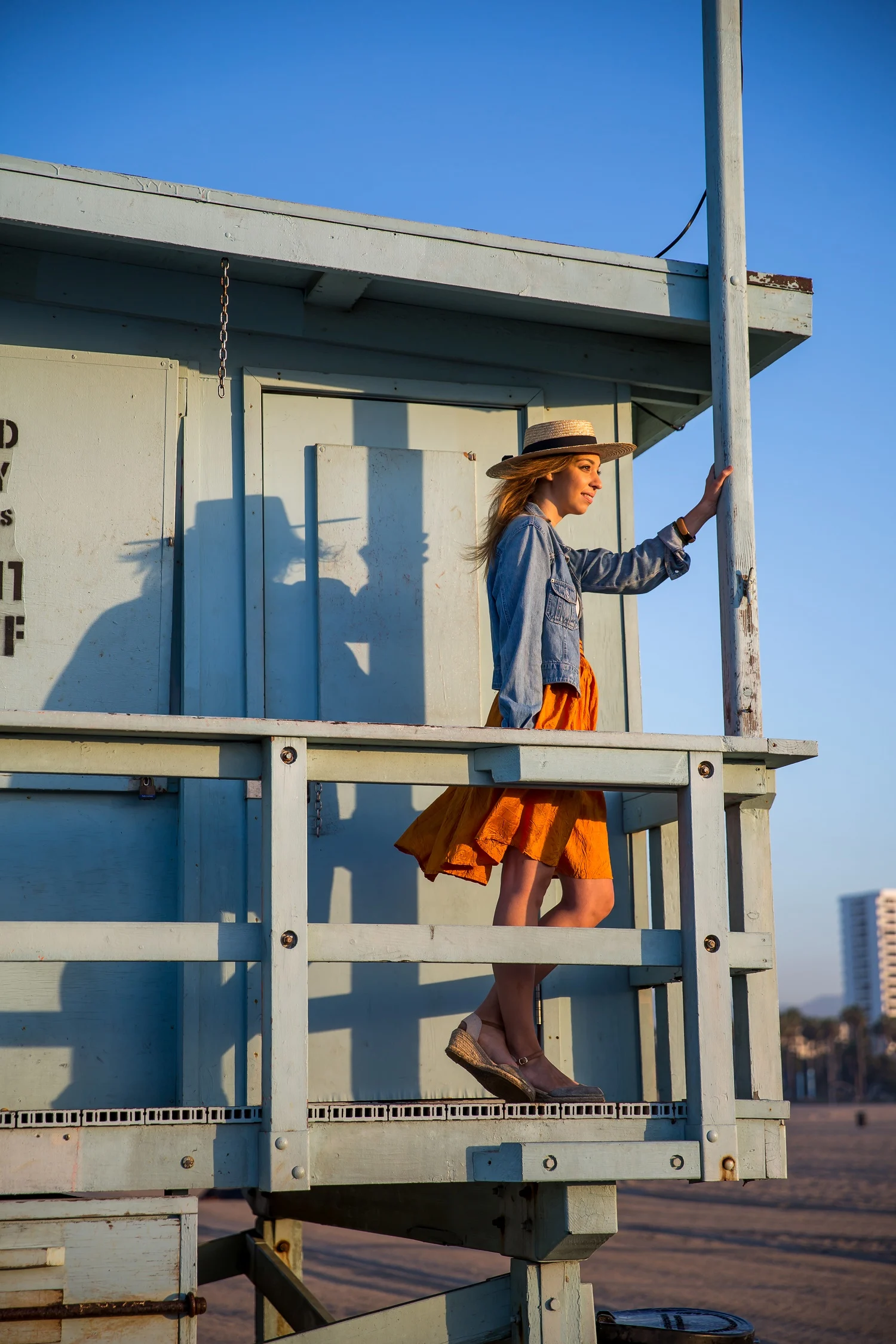 A woman wearing a denim jacket and an orange skirt in a lifeguard station
