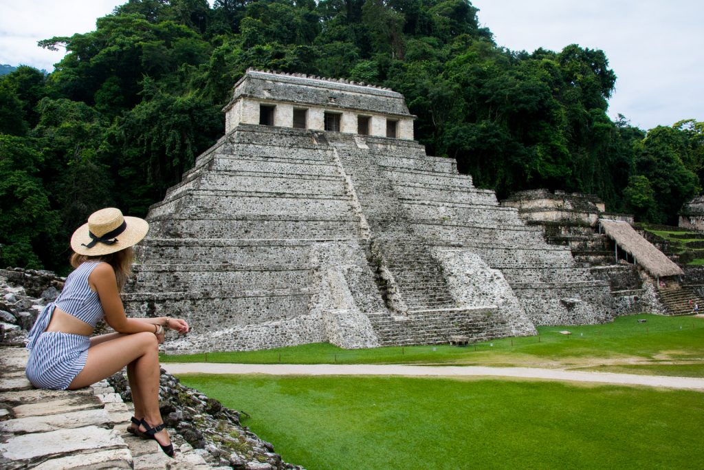 A woman looking at an impressive ancient pyramid in the site of Palenque