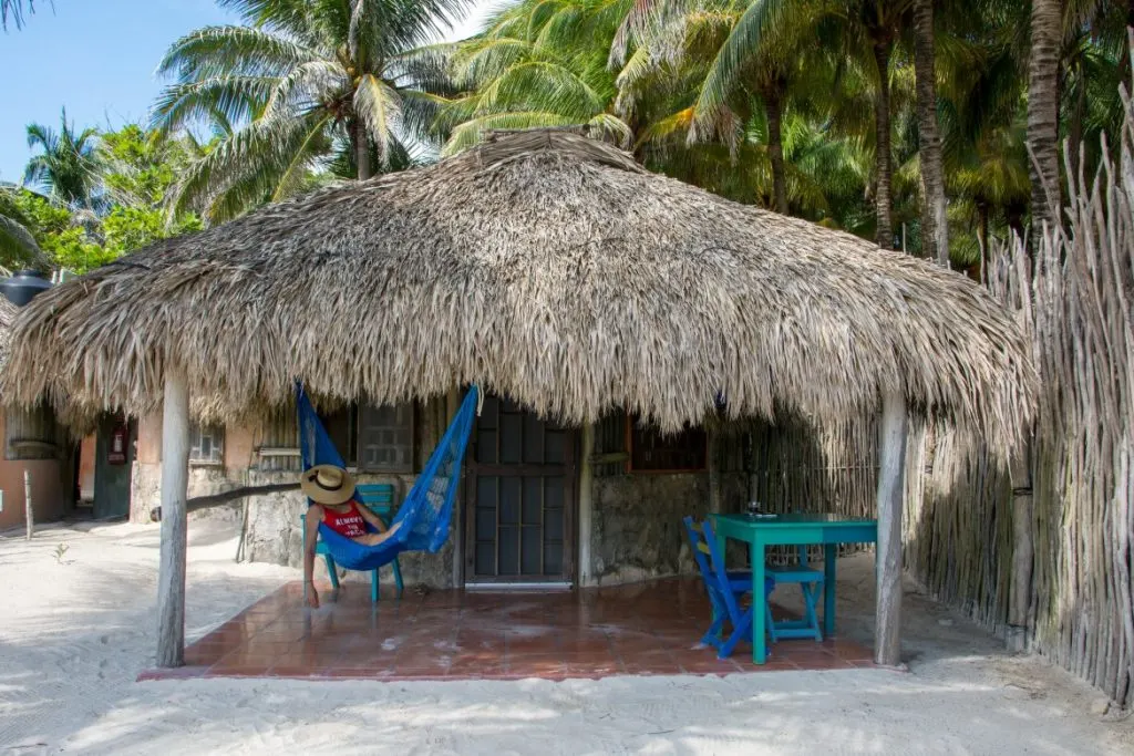 A woman relaxing on a hammock outside of a bungalow in Zamas, an eco hotel in Tulum