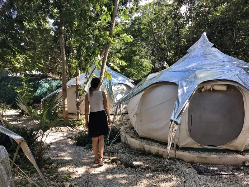 A woman walking among glamping tents in Harmony Glamping, Tulum