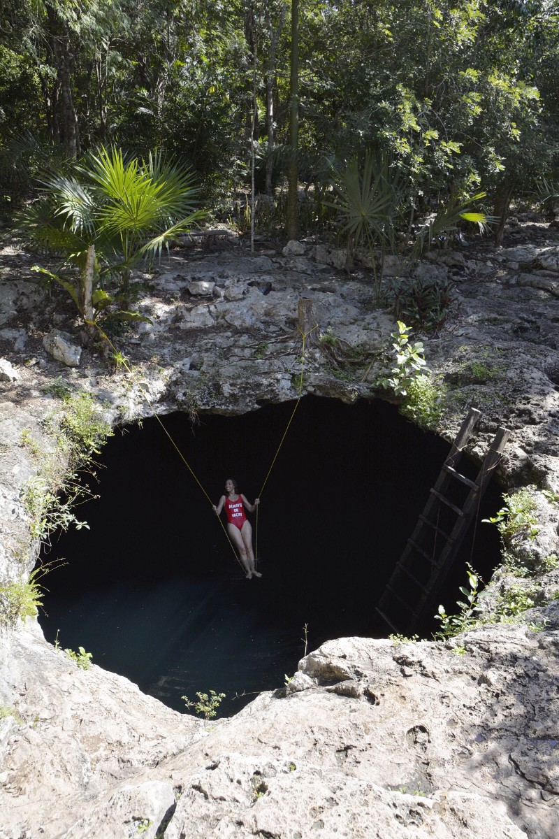 Image of woman swinging at Cenote Calavera in Mexico.