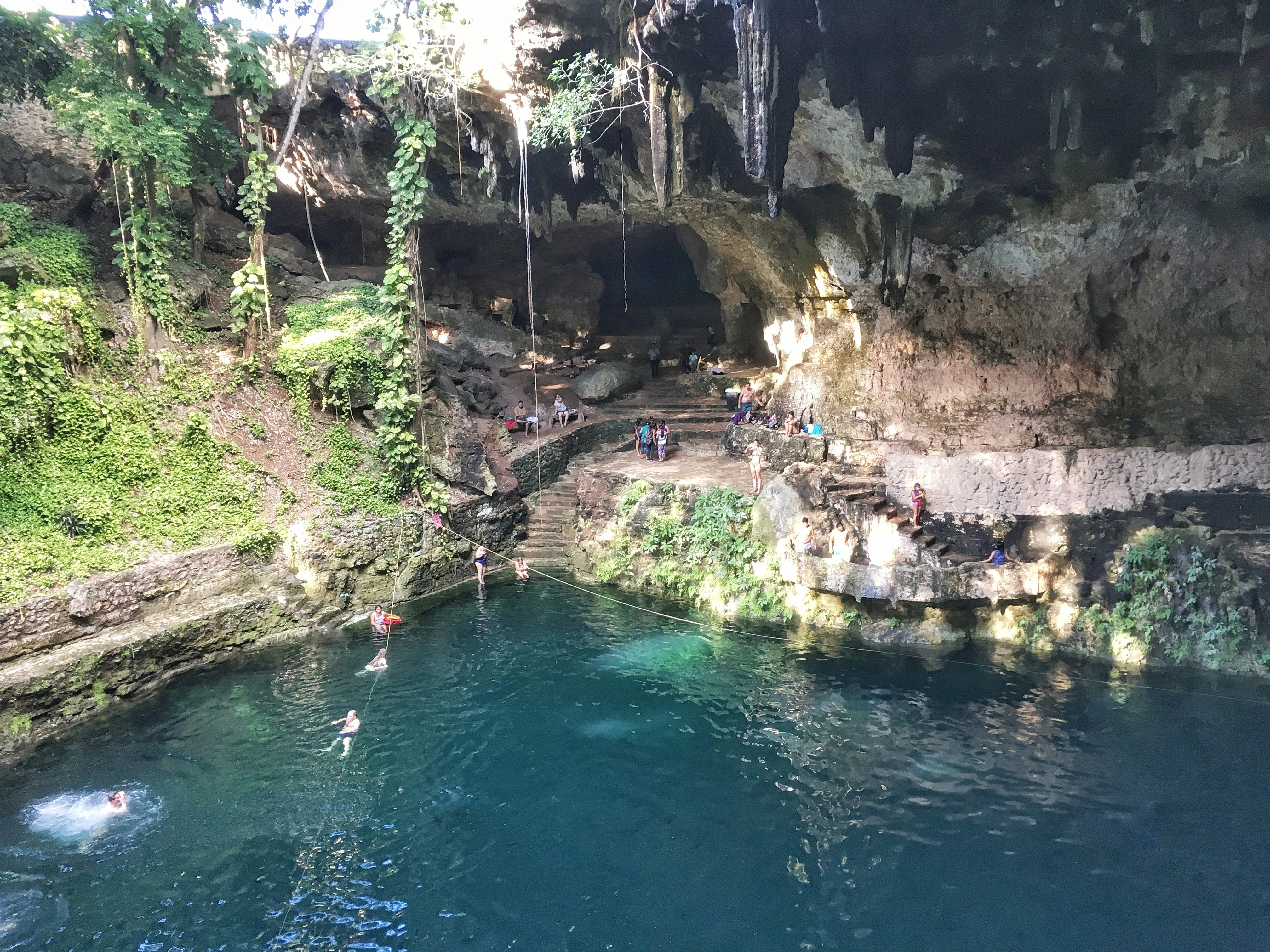 Image of Cenote Zaci, with the rock walls of a cave towering over it