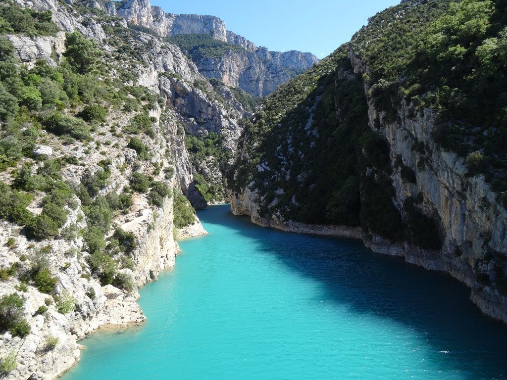 A gorge with turquoise water and vegetation-covered cliffs