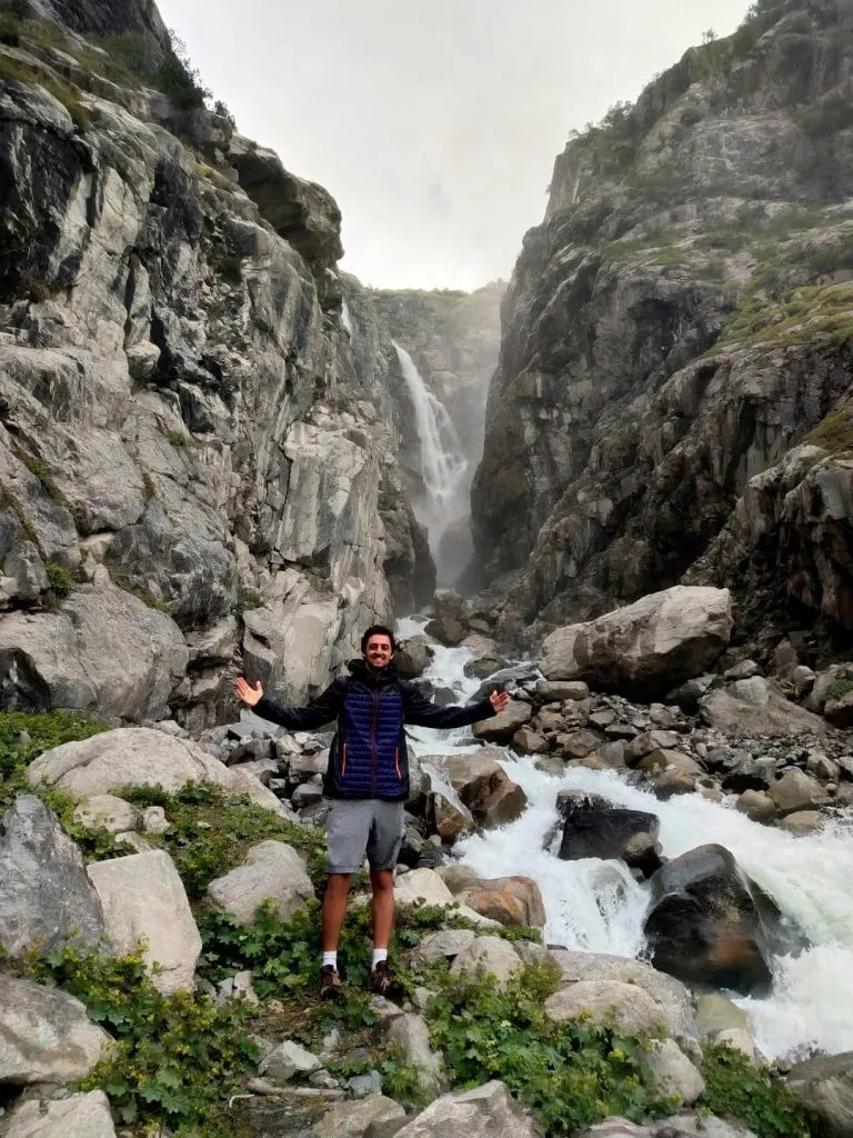 A man smiling in front of a big waterfall
