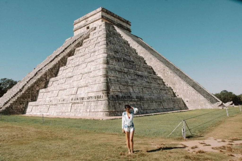 Woman standing in front of Chichen Itza pyramid.