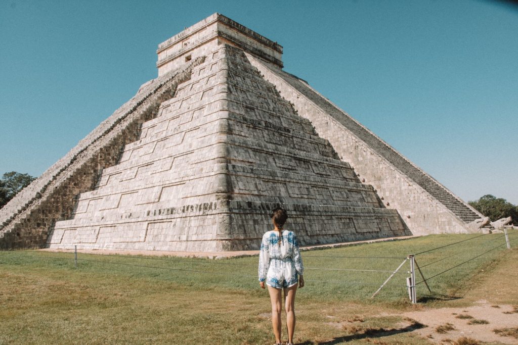 A woman standing in front of the Kukulcan Pyramid in Chichen Itza