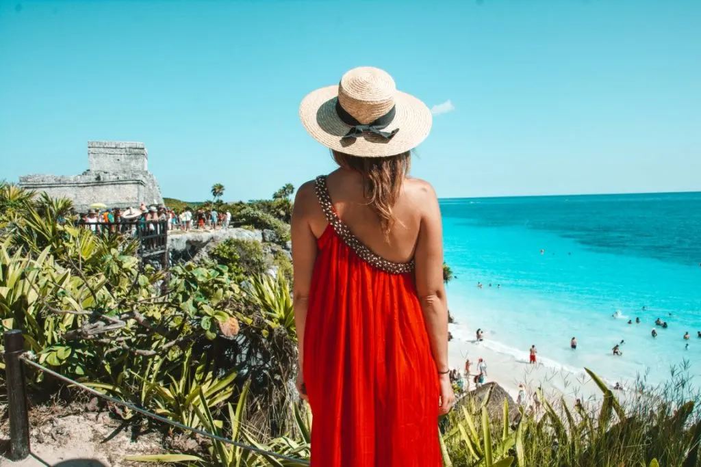 Woman looking at the Tulum ruins and Playa Ruinas in Tulum, Mexico.