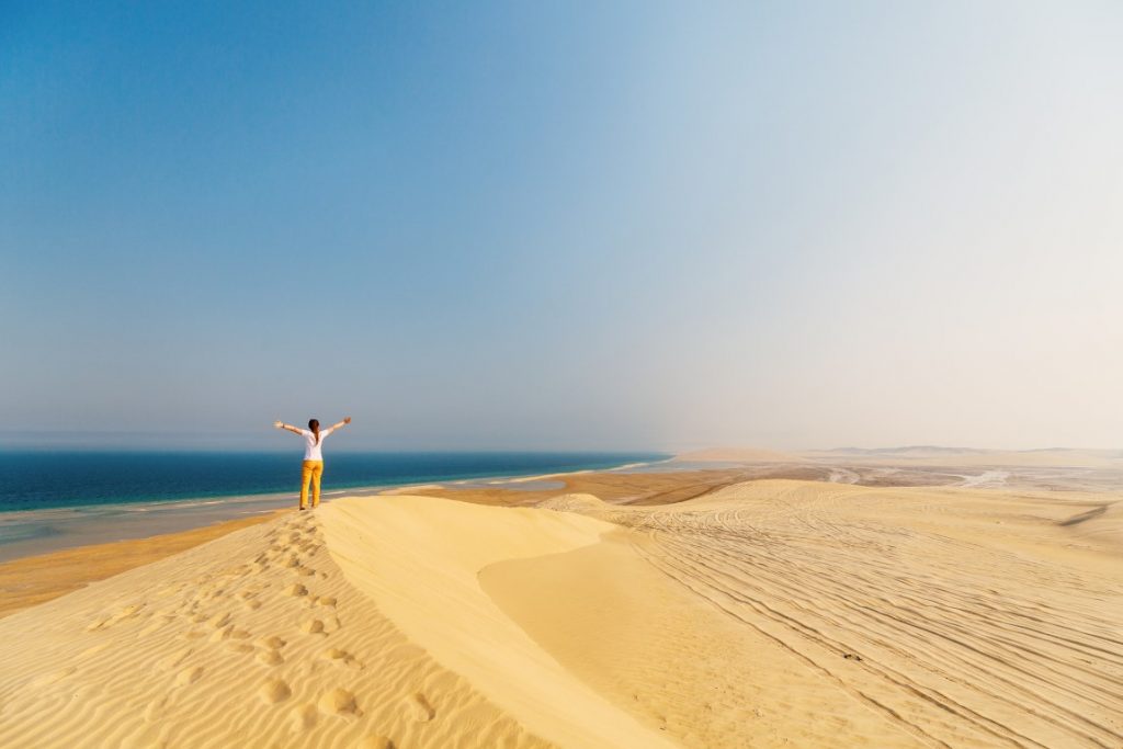 Image of a woman on a sand dune in Qatara, inserted in an article about the best Qatar desert safari from Doha.