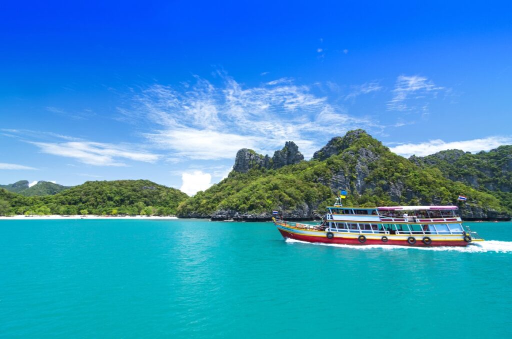 Image of a boat sailing on turquise waters with the island of Koh Samui in the background, inserted in a post about the best things to do in Koh Samui