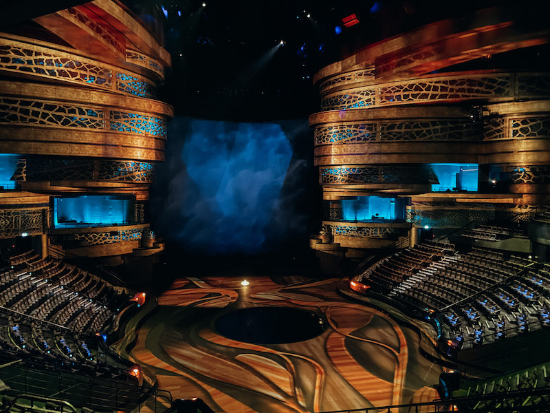 The empty stage of La Perle Dubai, with seating on both sides and golden and blue booths