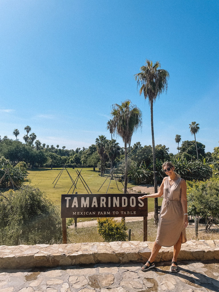 A woman posing in front of Los Tamarindos sign in Los Cabos