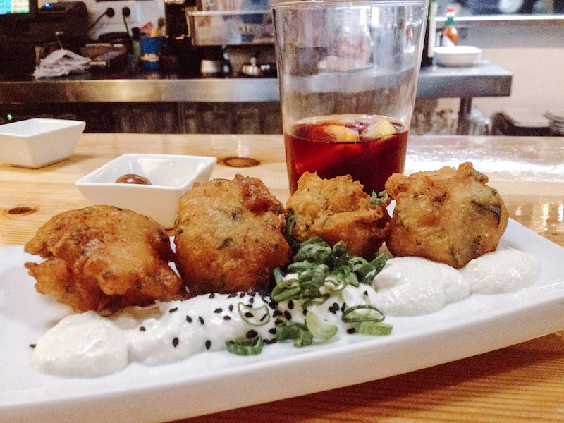 Small food bites in a bar, with a drink next to the plate
