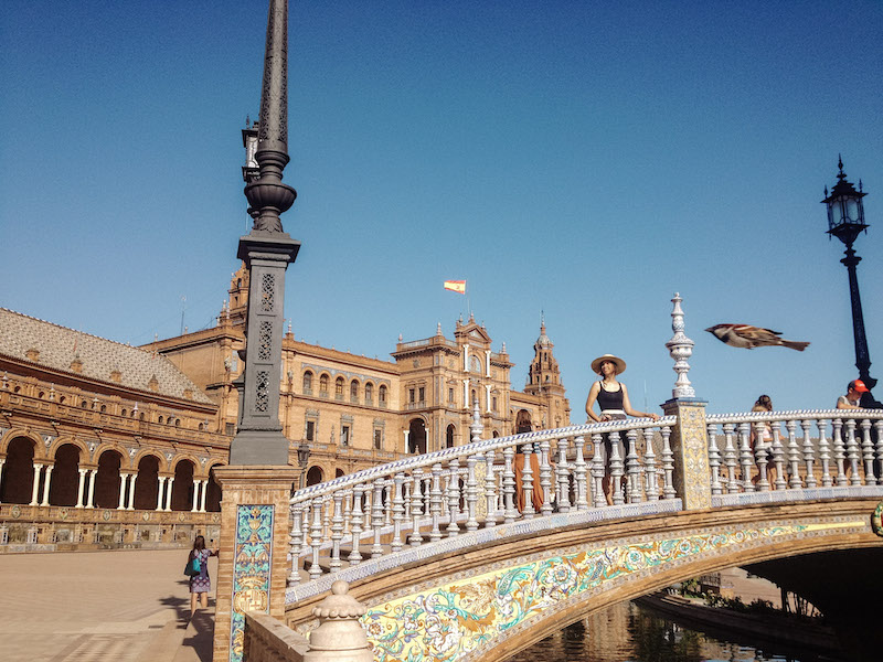 Image of a woman smiling on a beautiful bridge in Plaza de España, one of the most popular things to do in Seville 