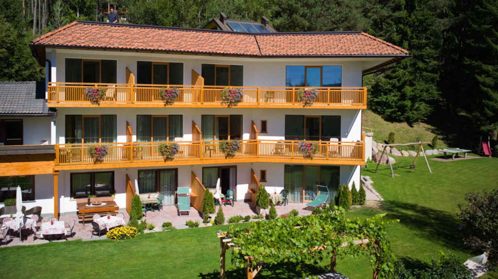 The white building with orange balconies of Apipura, one of the most enchanting eco hotels in South Tyrol