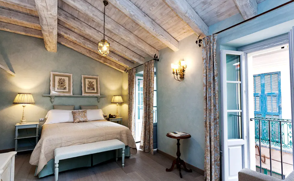 An elegant bedroom with a balcony in Relais del Maro, inserted in a post about eco hotels in Italy 