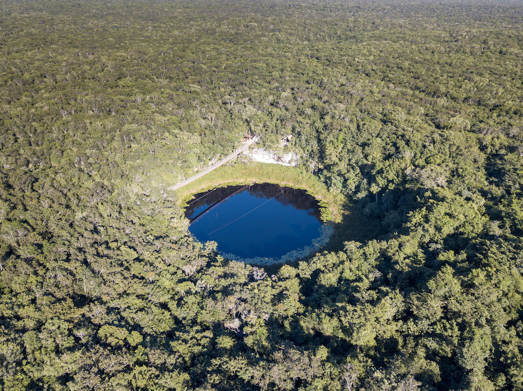 Drone image of a cenote in the jungle inserted in a post about the best cenote tours from Cancun.