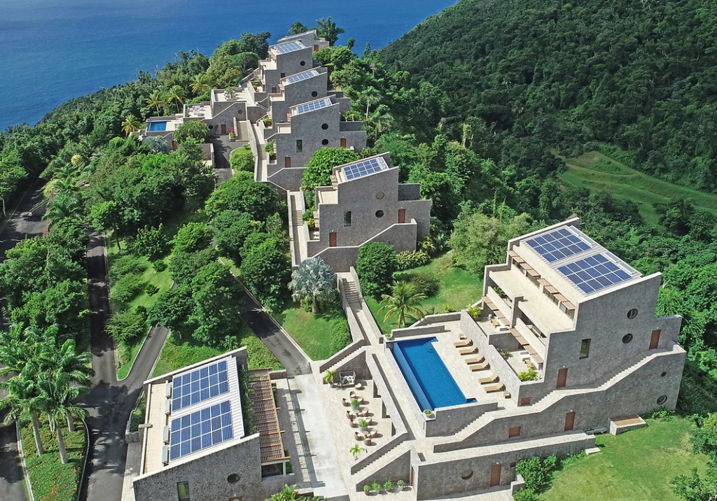 Image of Coulibri Ridge resort seen from above, with granite buildings set amidst the greenery, solar panels on the roofs, and swimming pools on the terraces