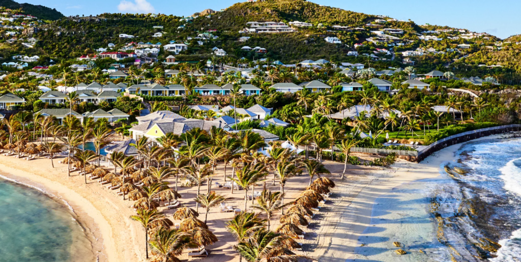 Image of one of the best eco lodges in the Caribbean, a peninsula featuring a beach and the sea on both sides, and the land dotted in pakm trees and villas