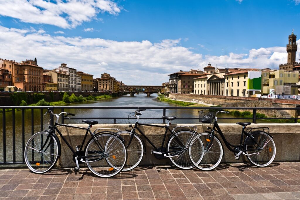 Image of three black bikes with the Arno River and Ponte Vecchio in the background, inserted in a post about bike tours in Florence