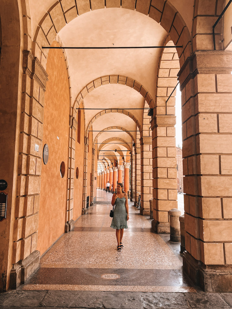 Image of a woman walking under the porticoes during a walking tour in Bologna.