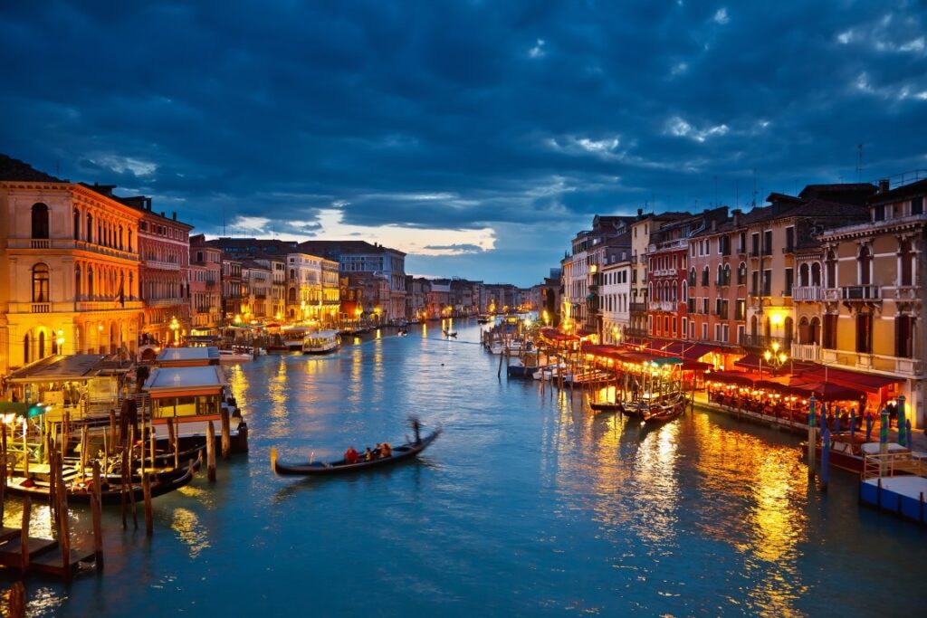 Image of the Grand Canal at night, lined by Venice's lit-up waterfront on both sides, a perfect setting for Venice ghost tours.