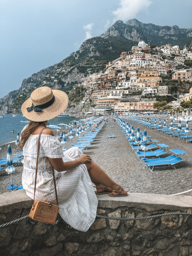 Woman from the back sitting and looking at the Marina Grande beach in Positano, Amalfi Coast.