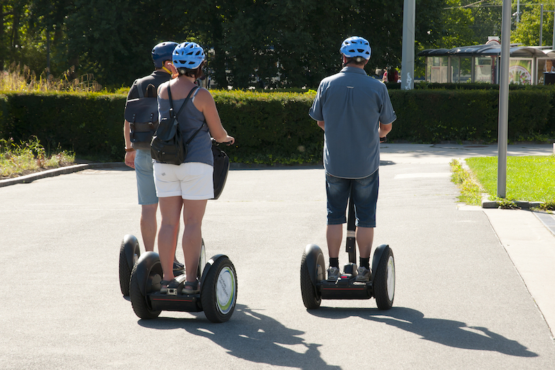 Three people on a Segway tour in Rome riding segways with a helmet on.