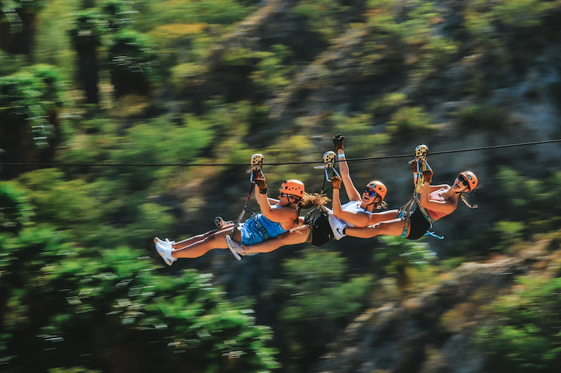 3 women ziplining in Cabo san Lucas wearing orange hemets.