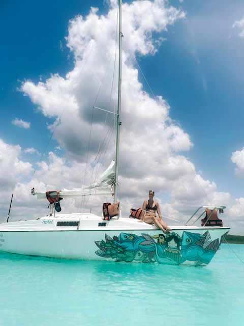 Girl sitting on the deck of a sailing boat in Bacalar. Image inserted in a post about the best Bacalar tours