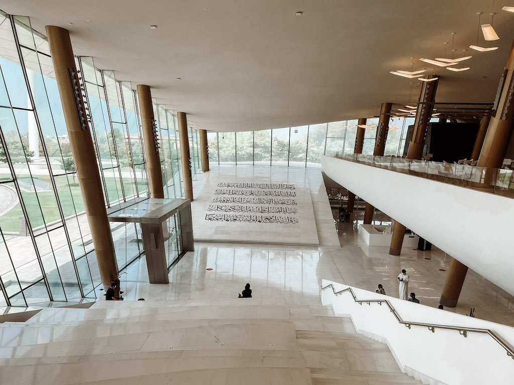 The interior of a museum with a wide marble staircase and floor-to-ceiling windows