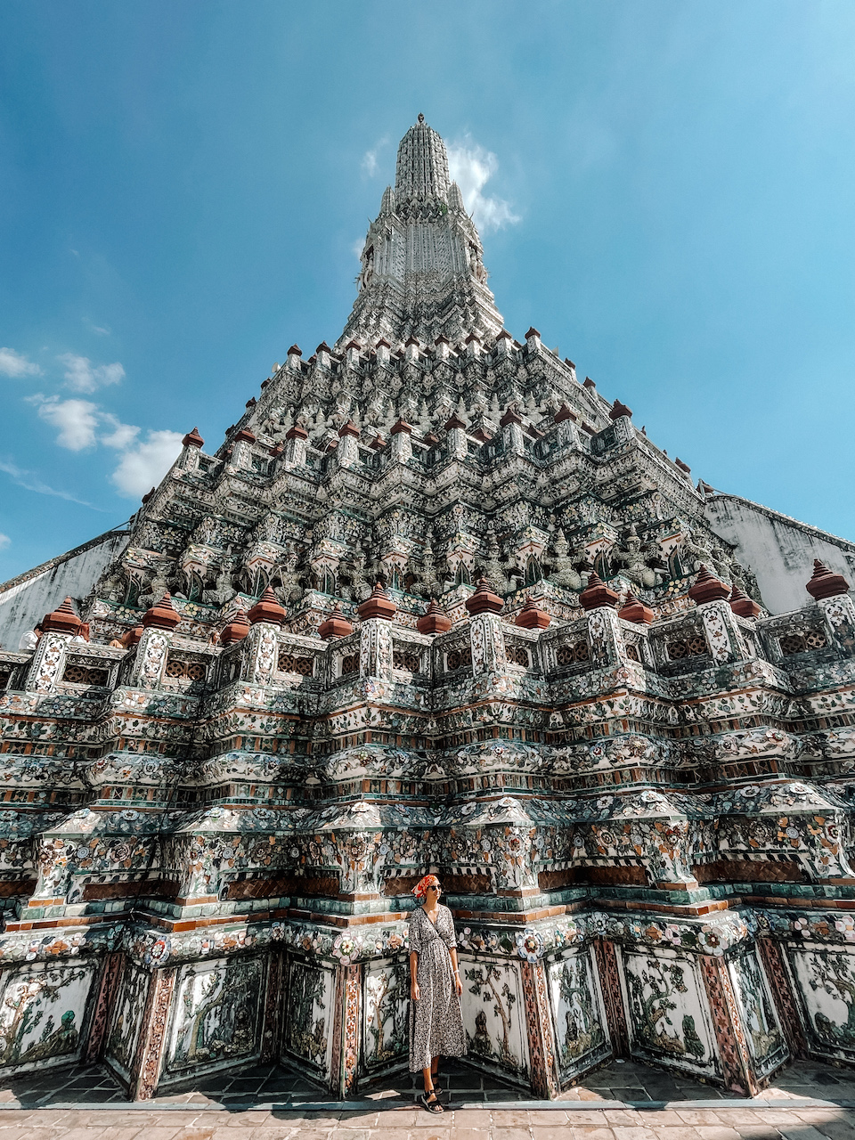 A woman standing in front of an intricate pagoda in a Thai temple
