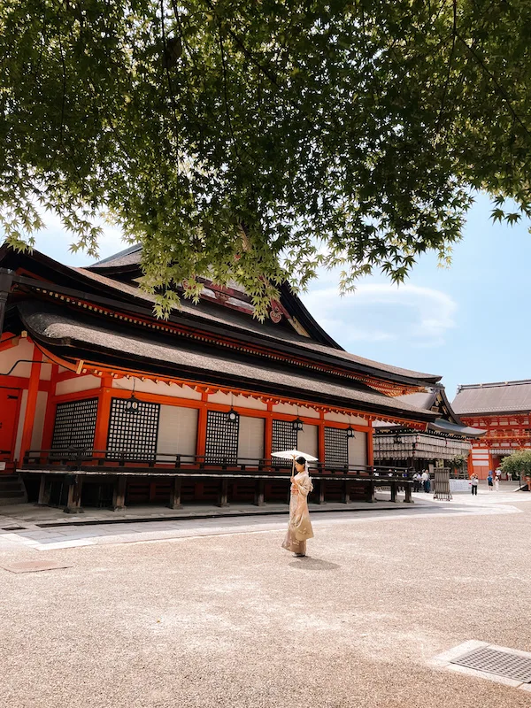A Japanese temple, and a woman in a kimono walking past it