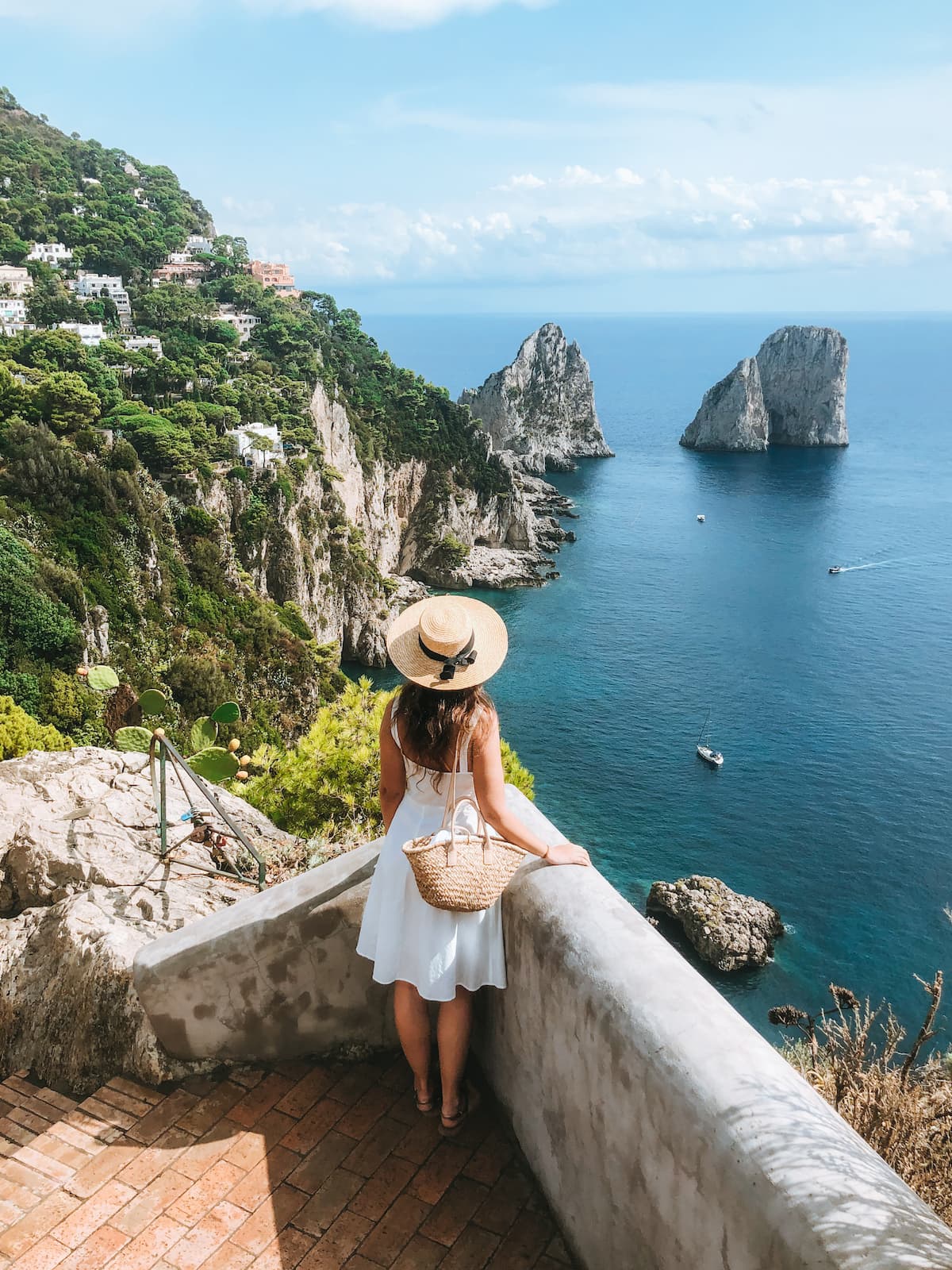 A woman looking toward the Faraglioni rocks from a viewpoint on Capri.