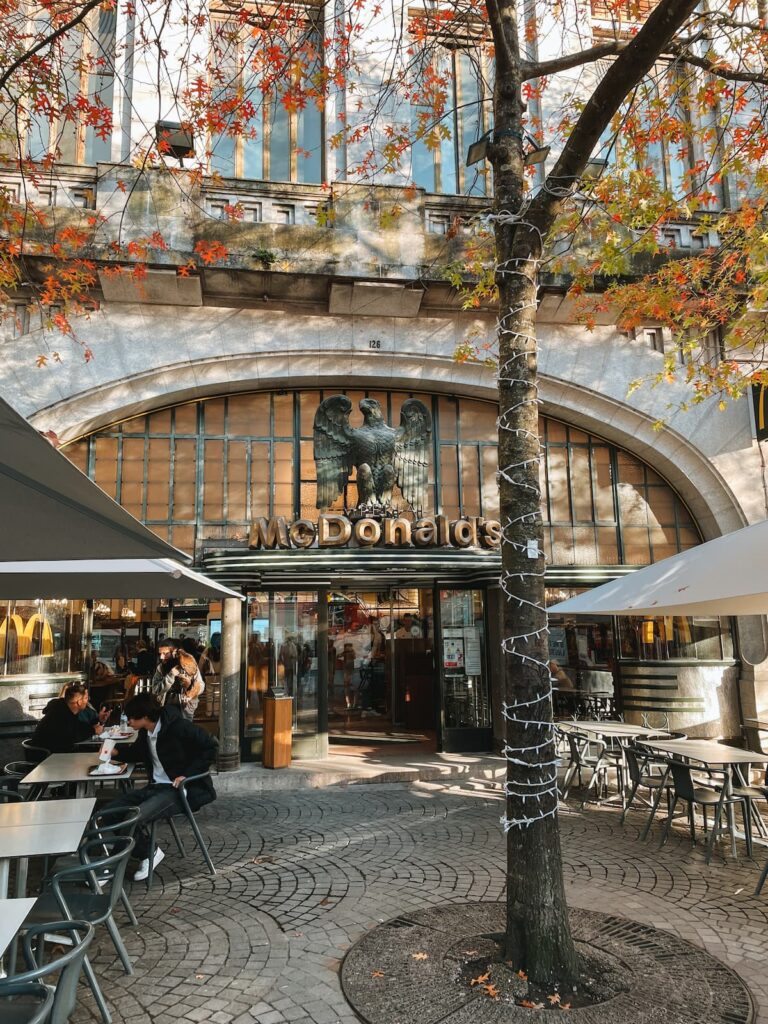Facade of McDonald’s Imperial restaurant in Porto with outdoor seating and autumn trees