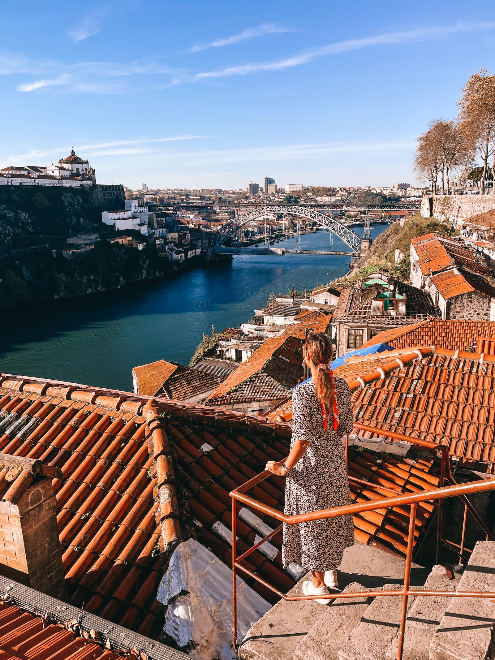 Woman standing on a terrace overlooking Porto rooftops and the Dom Luís I Bridge over the Douro River