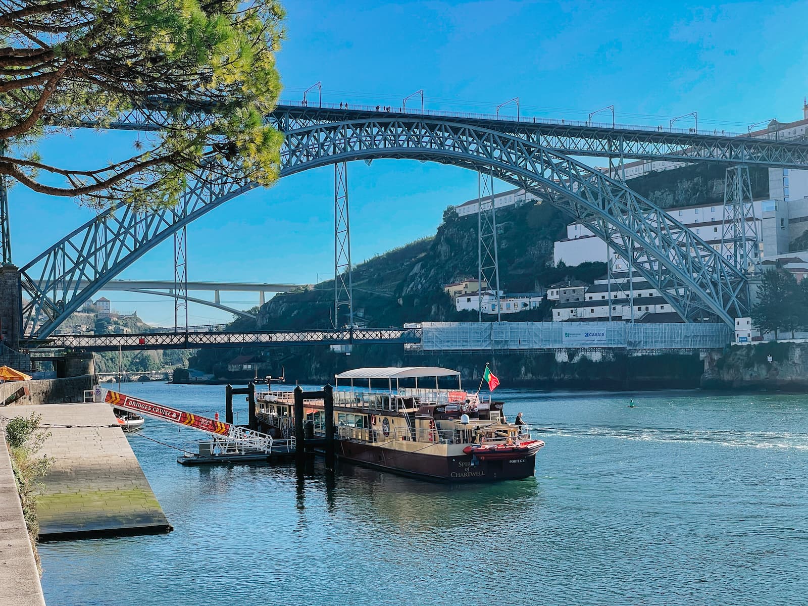 Boat docked on the Douro River beneath Dom Luís I Bridge in Porto