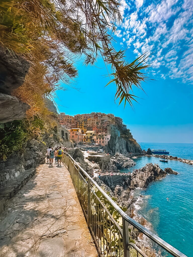 Coastal walkway in Manarola overlooking the colorful cliffside village and the turquoise sea in Cinque Terre.