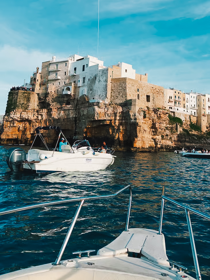 Boat tour in front of the cliffs and whitewashed buildings of Polignano a Mare.