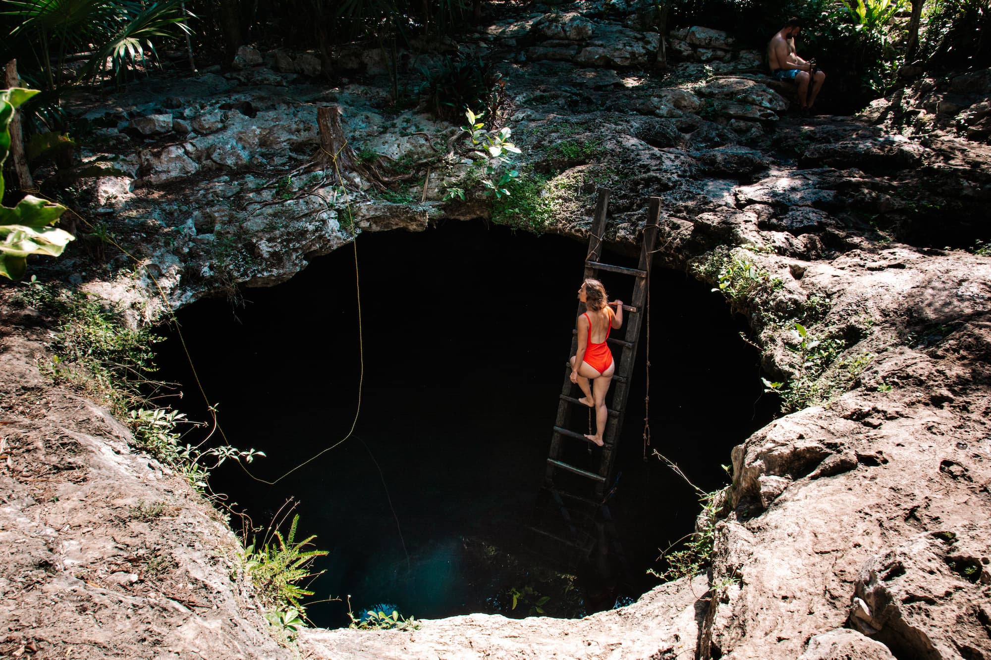 Stef climbing the wooden ladder at Cenote Calavera in Tulum, Mexico.