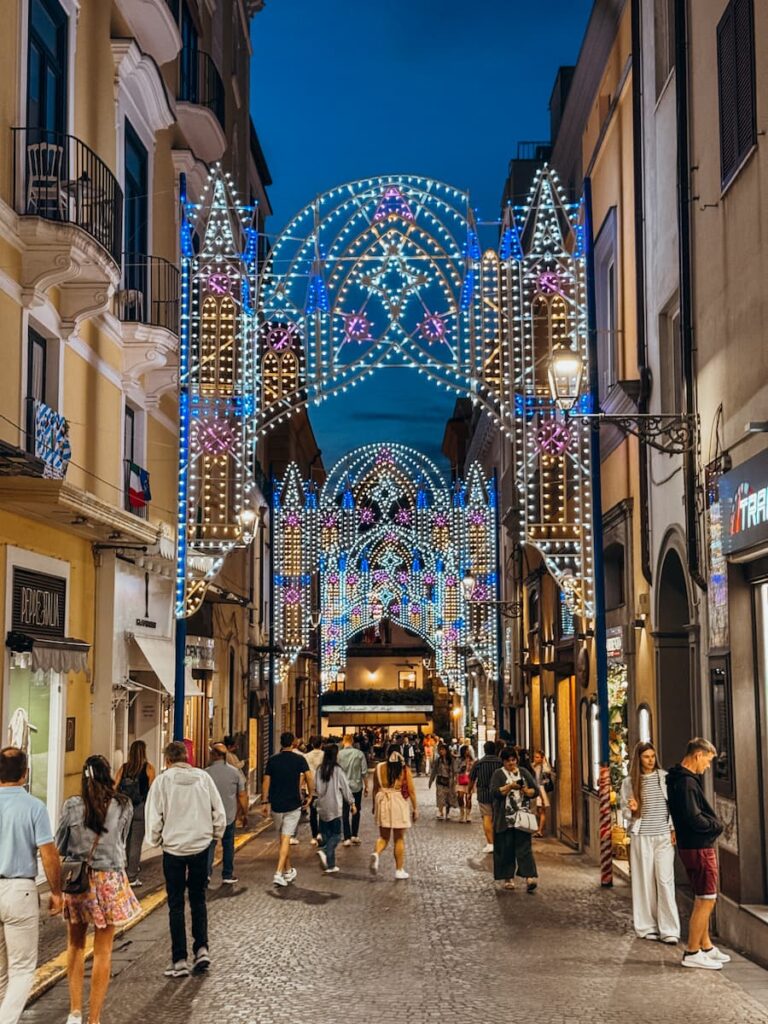 Decorative lights above a busy street in Sorrento’s old town at night.