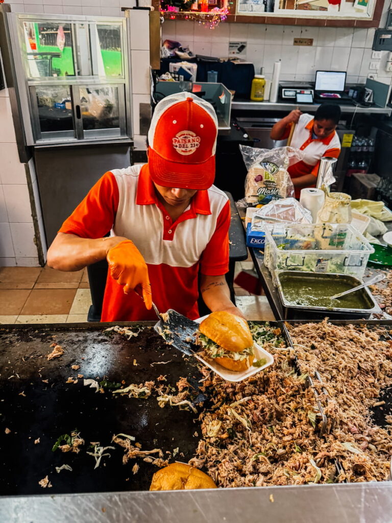 A vendor preparing a torta at a food stall in downtown Cancun.
