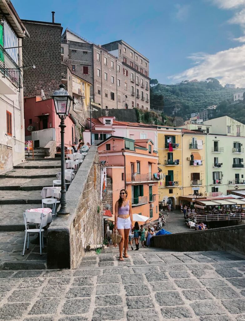 A woman on the stone steps at Marina Grande, with colorful Sorrento buildings behind her.
