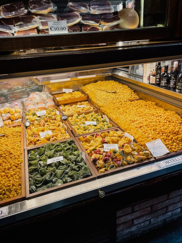 Fresh tortellini and other pasta displayed in a shop on Via Pescherie Vecchie.