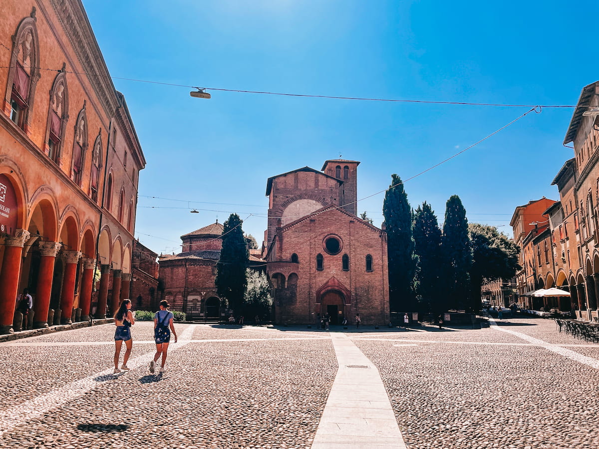 People walking across Piazza Santo Stefano toward Bologna’s Seven Churches complex.