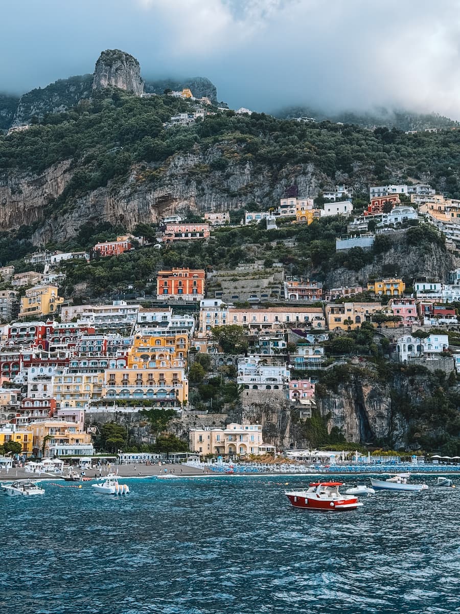 Boats off Positano’s beach, with colorful hillside buildings and steep green cliffs in the background.